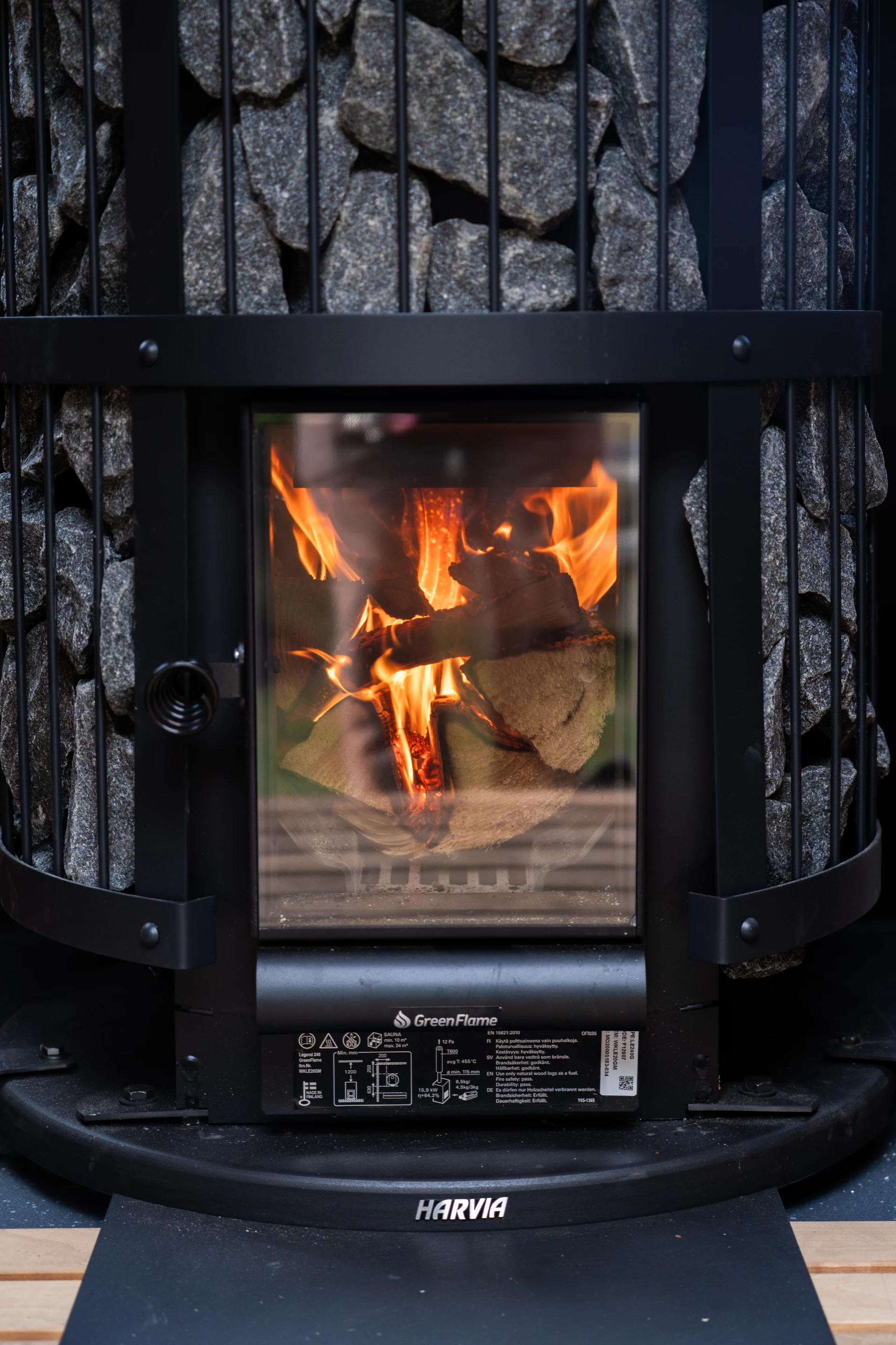 Close view of the sauna stove, flames and logs behind its glass door